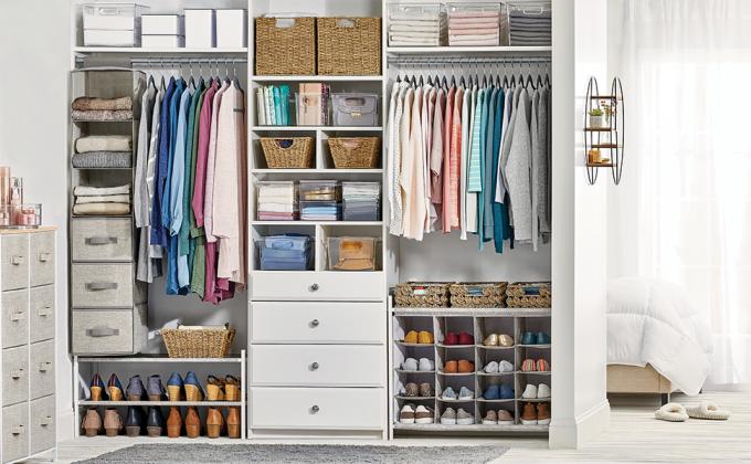 Cream fabric dressers, totes, clear bins, natural baskets, clothing in a white closet setting, bed